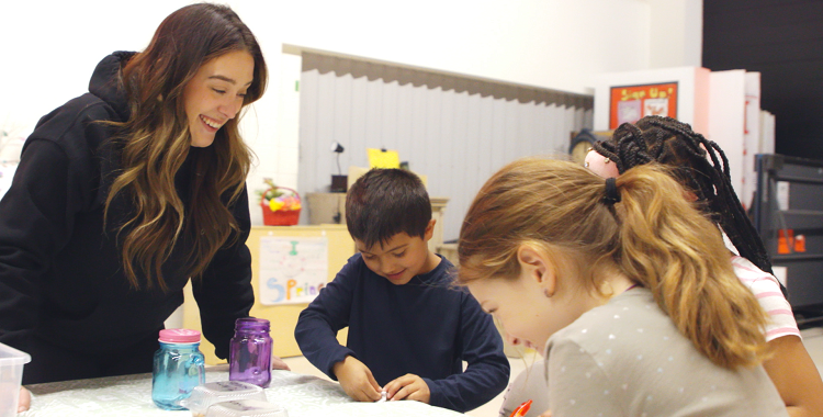 An educator interacts with three children who do arts and crafts in the Before & After School program.