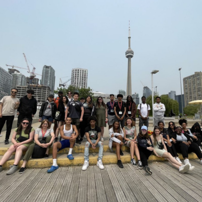 Youth from Toronto and Halifax gather on a stoop with the CN Tower in the background.