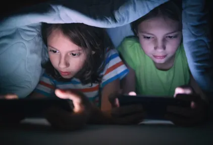 Boy and girl playing games on mobile phone in their bed stock photo
