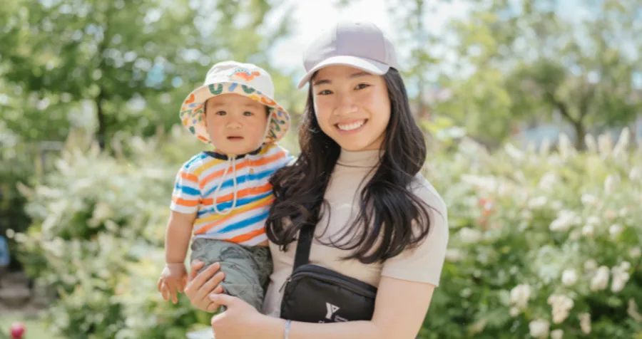 A child care educator holds a child in a Y M C A child care outdoor play area.