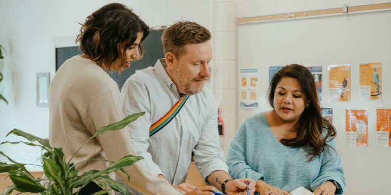 Three child care educators talk together while planning.