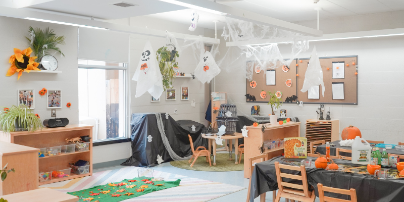 A preschool room features fall decor, including a crafted pumpkin and spooky ghost decorations.