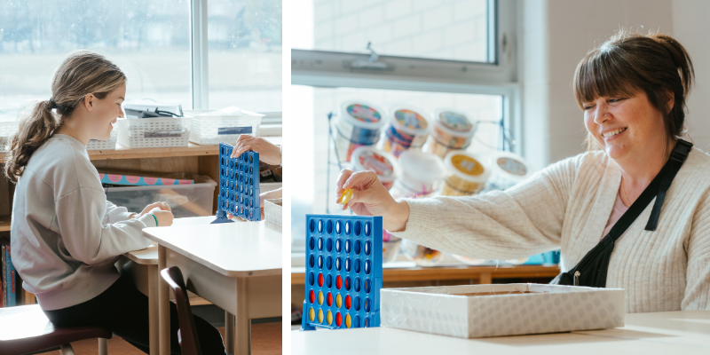 A child care educator plays Connect Four with a school-aged child.