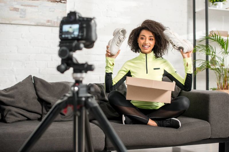Image of a female youth unboxing items in front of a camera.