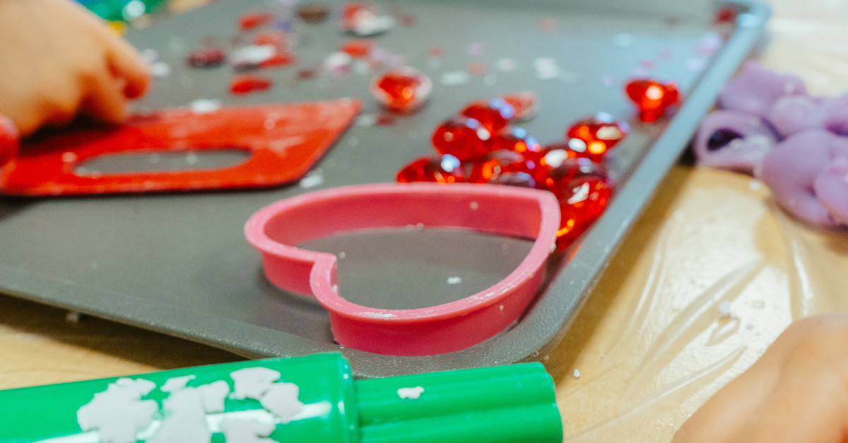 A pink, heart-shaped cookie cutter on a baking pan.