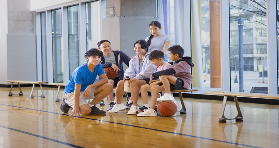 A smiling family takes a break from playing basketball at the Y M C A of Greater Toronto.