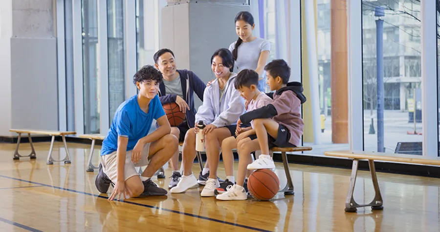 A smiling family takes a break from playing basketball at the Y M C A of Greater Toronto.