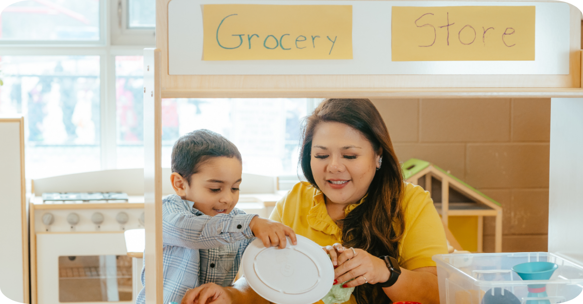 Educator and child playing at a pretend grocery store setup in a YMCA child care room.