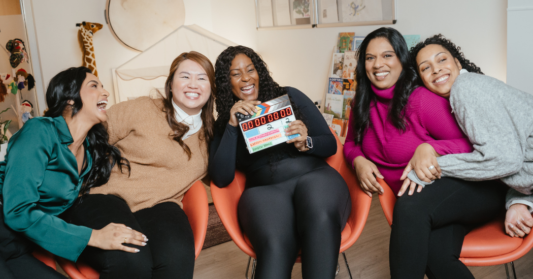 Five child care supervisors and managers smile while holding a clapboard.