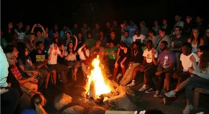 A group of people cheering around a campfire at night