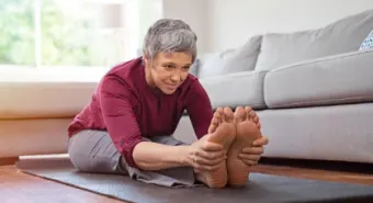 An older adult woman stretching on a yoga mat