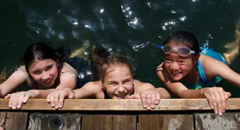 girls in water hanging off of dock