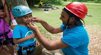 YMCA staff helping child put on helmet