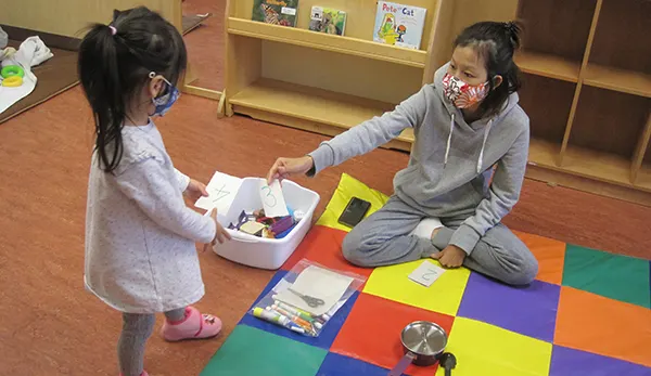 a teacher handing a student a toy with masks on
