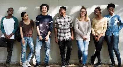 a diverse group of youth standing against a wall