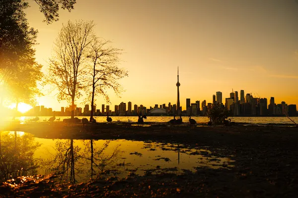a silhouette of the skyline of Toronto with the yellow sun peaking out