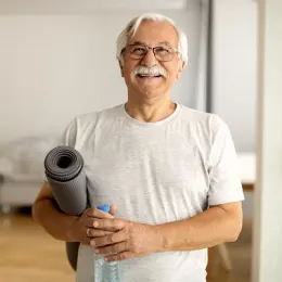 older man at home with yoga mat