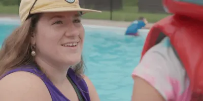 YMCA staff talking to a child next to the pool
