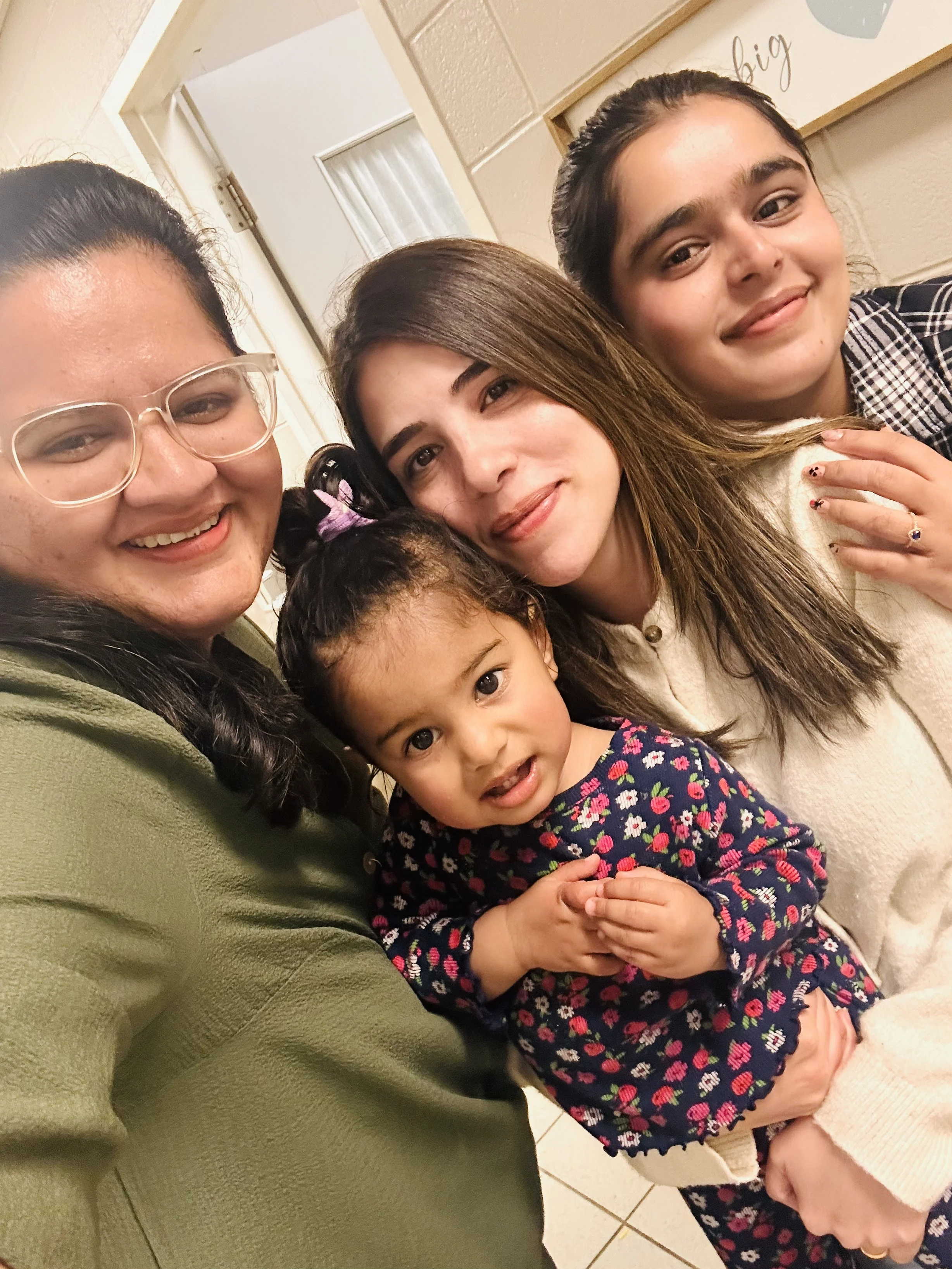 Three adults pose with an infant.