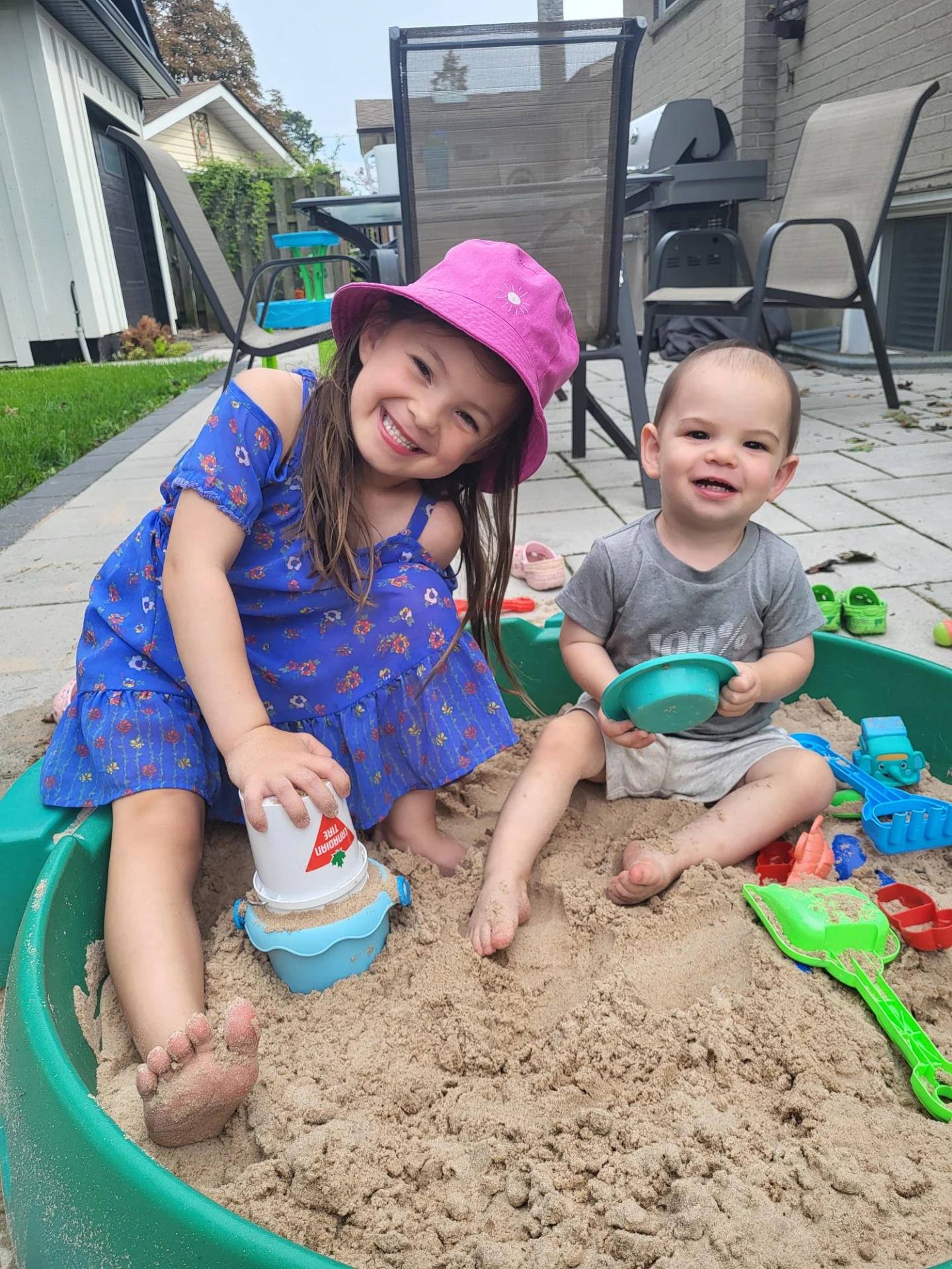 Two young children play happily in a sandbox
