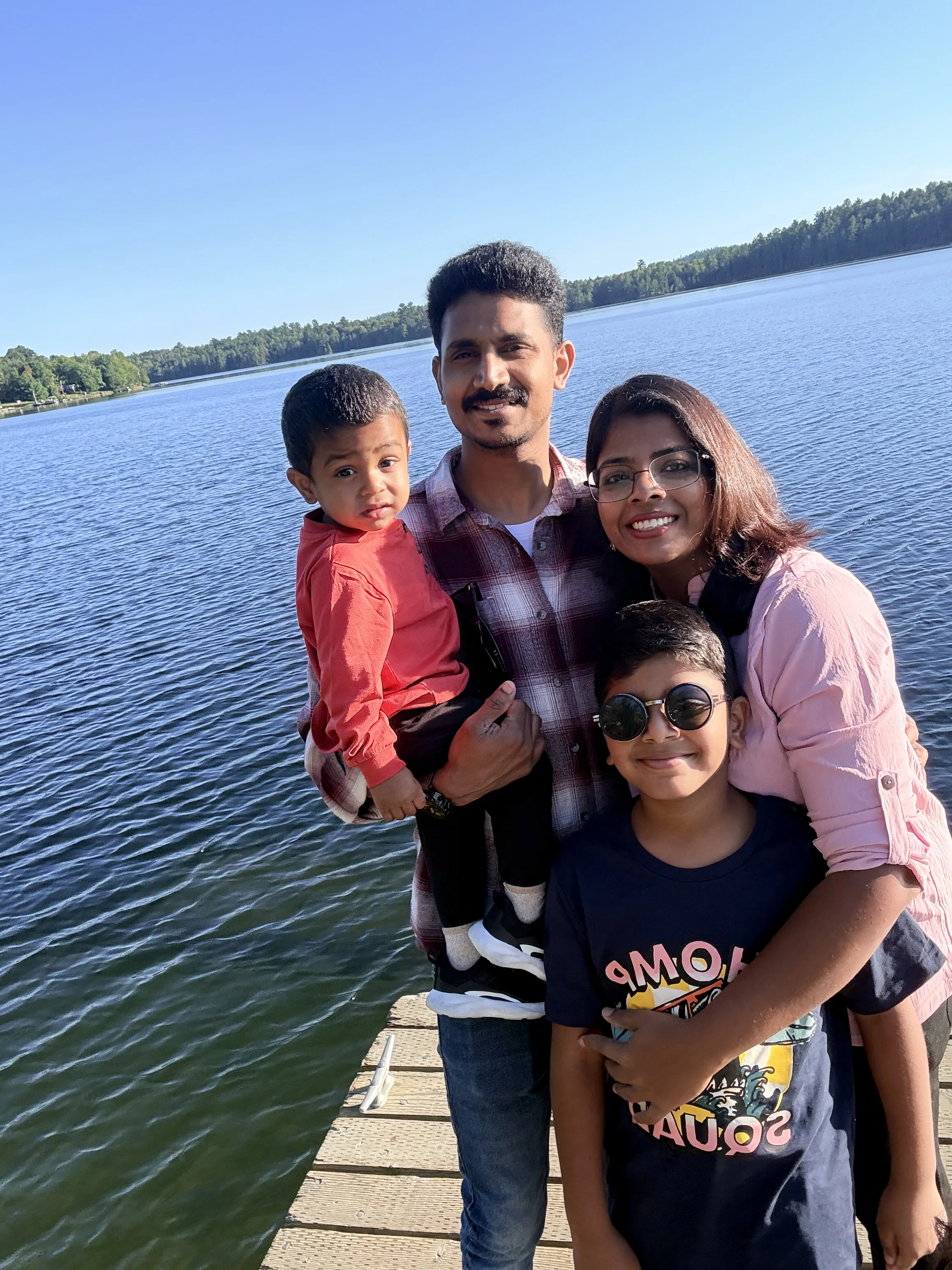 Two adults, two children outdoors with a lake behind them.
