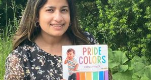 Child care worker holds up a book for children called "Pride Colours"