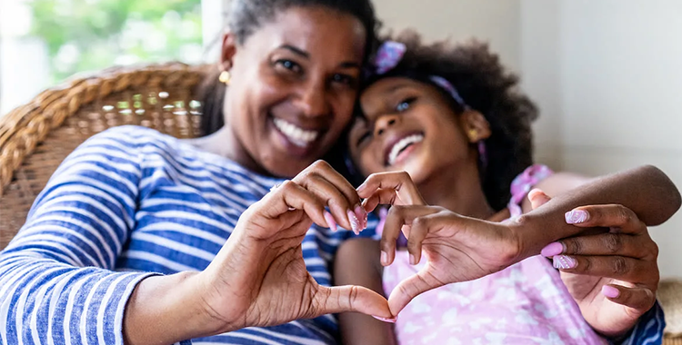 Portrait of parent and child embracing doing heart gesturing at home