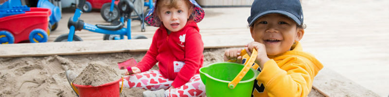 A boy and girl toddler child playing in a sandbox at a YMCA Child Care Centre